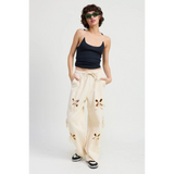 woman wearing Emory Park wide leg laser cutout cotton beach pants in cream with floral cutout details