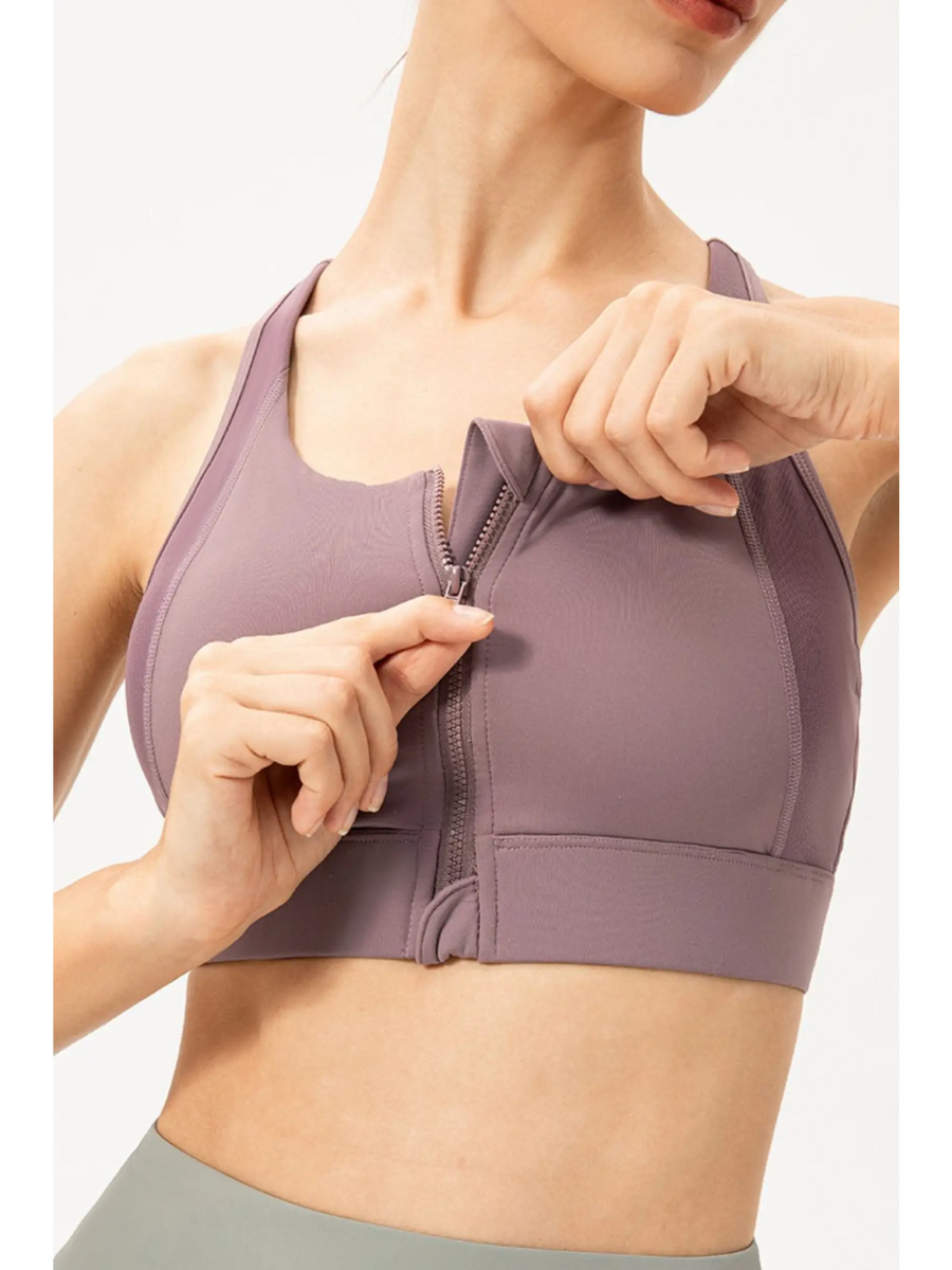 Babe Beachwear light blue zip front sports bra being zipped up on a woman in a close-up