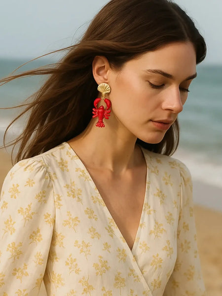 Trendsi Lobster Drop Earrings Resort in red worn by woman at the beach with beige floral dress
