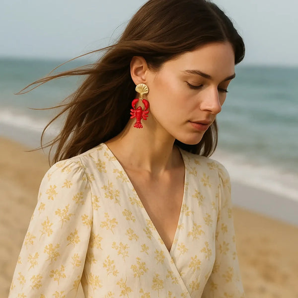 Trendsi Lobster Drop Earrings Resort in red worn by woman at the beach with beige floral dress
