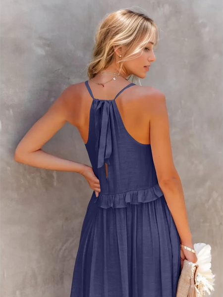Back view of woman wearing flowy pink ruffle maxi dress with halter neck and bow tie
