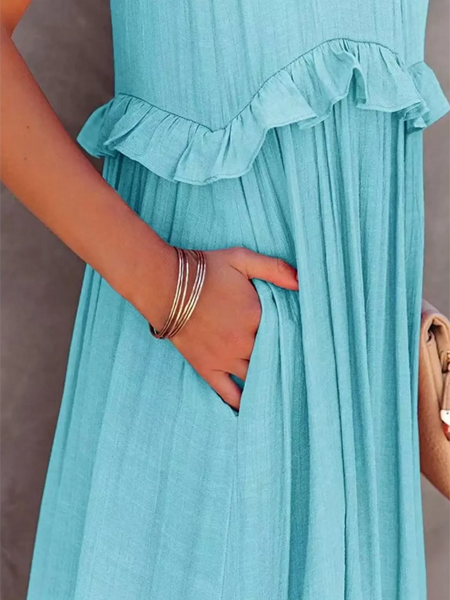 Close-up of a blue maxi dress with ruffle detail and pocket, styled with bracelets and a beige handbag