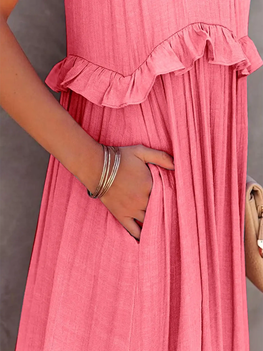 Close-up of flowy pink ruffle maxi dress by Trendsi with hand in side pocket and silver bracelets