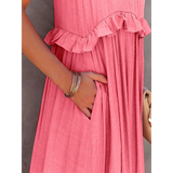 Close-up of flowy pink ruffle maxi dress by Trendsi with hand in side pocket and silver bracelets
