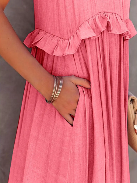 Close-up of flowy pink ruffle maxi dress by Trendsi with hand in side pocket and silver bracelets