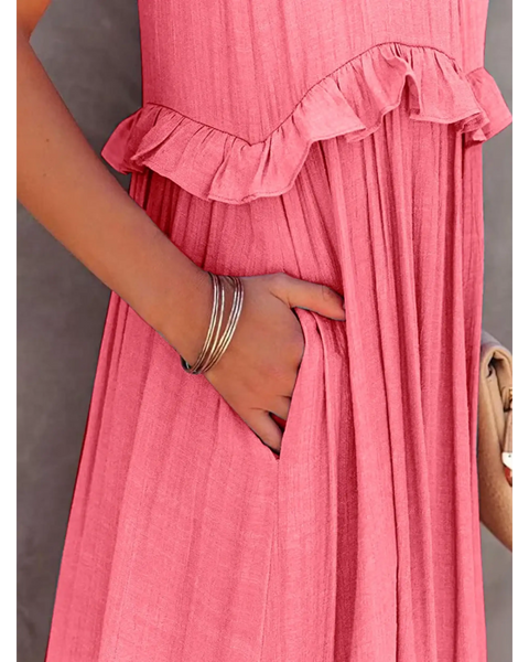 Close-up of flowy pink ruffle maxi dress by Trendsi with hand in side pocket and silver bracelets