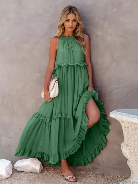 Green maxi dress with ruffle details and flowy layers worn by a woman holding a white clutch