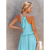 Back view of flowy pink ruffle maxi dress by Trendsi with tied halter neck and ruffled waist detail