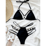 Beach Babes black bikini swimsuit with unique strap details Miami style swimwear for women laid on white fabric