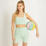 Mint green high waist active shorts with pocket worn by woman holding a colorful basketball
