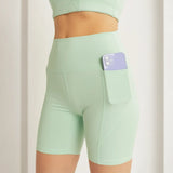 Trendsi mint green high waist active shorts with pocket holding a smartphone