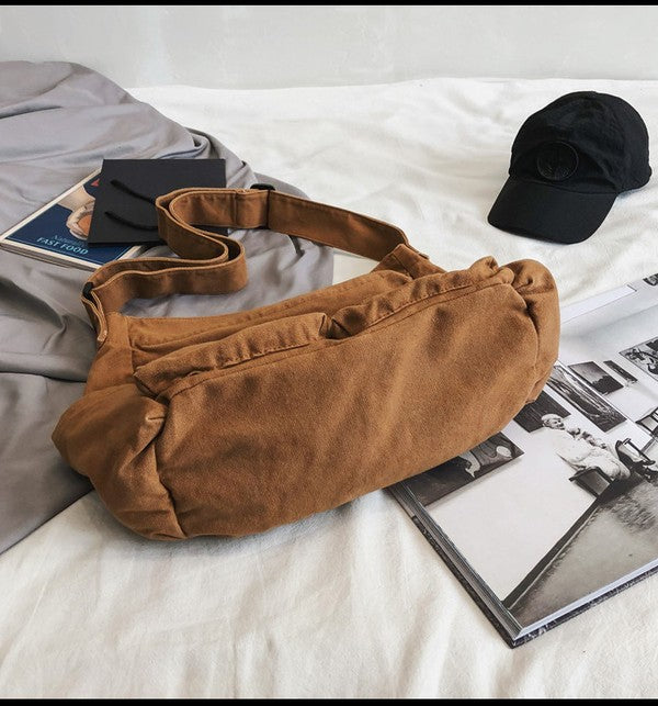 Brown Nova Oversized Canvas Messanger Bag by Babe Beachwaer on white surface with black cap and magazines