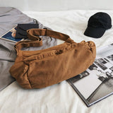Brown Nova Oversized Canvas Messanger Bag by Babe Beachwaer on white surface with black cap and magazines