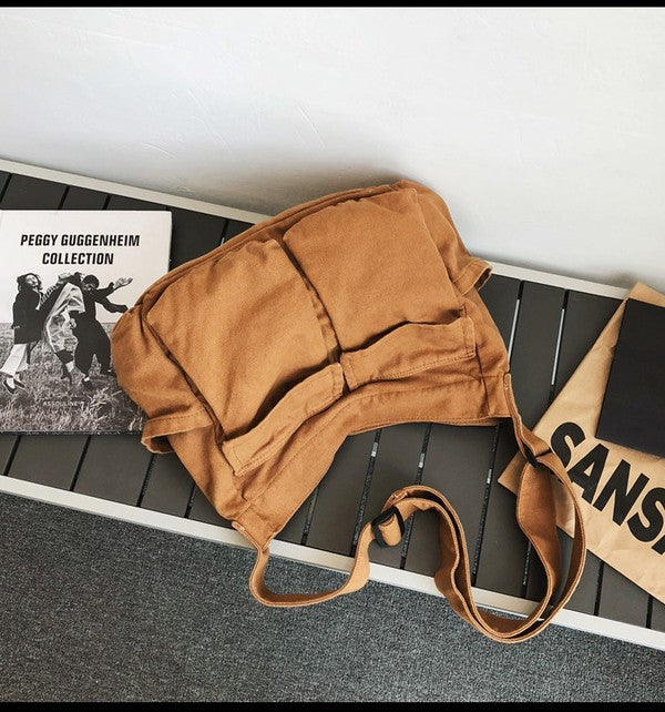 Babe Beachwaer Nova Oversized Canvas Messanger Bag in brown laid on a bench with books
