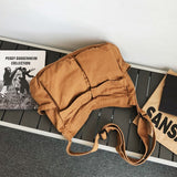 Babe Beachwaer Nova Oversized Canvas Messanger Bag in brown laid on a bench with books