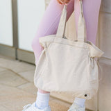Nylon Lightweight Weekender Gym Bag by Babe Beachwear in beige held by person in pink leggings and white sneakers