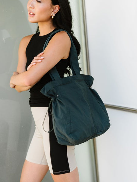 Nylon Lightweight Weekender Gym Bag by Babe Beachwaer in dark green carried by a woman in sporty outfit