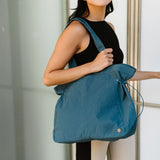 Woman carrying Babe Beachwear Nylon Lightweight Weekender Gym Bag in blue over shoulder