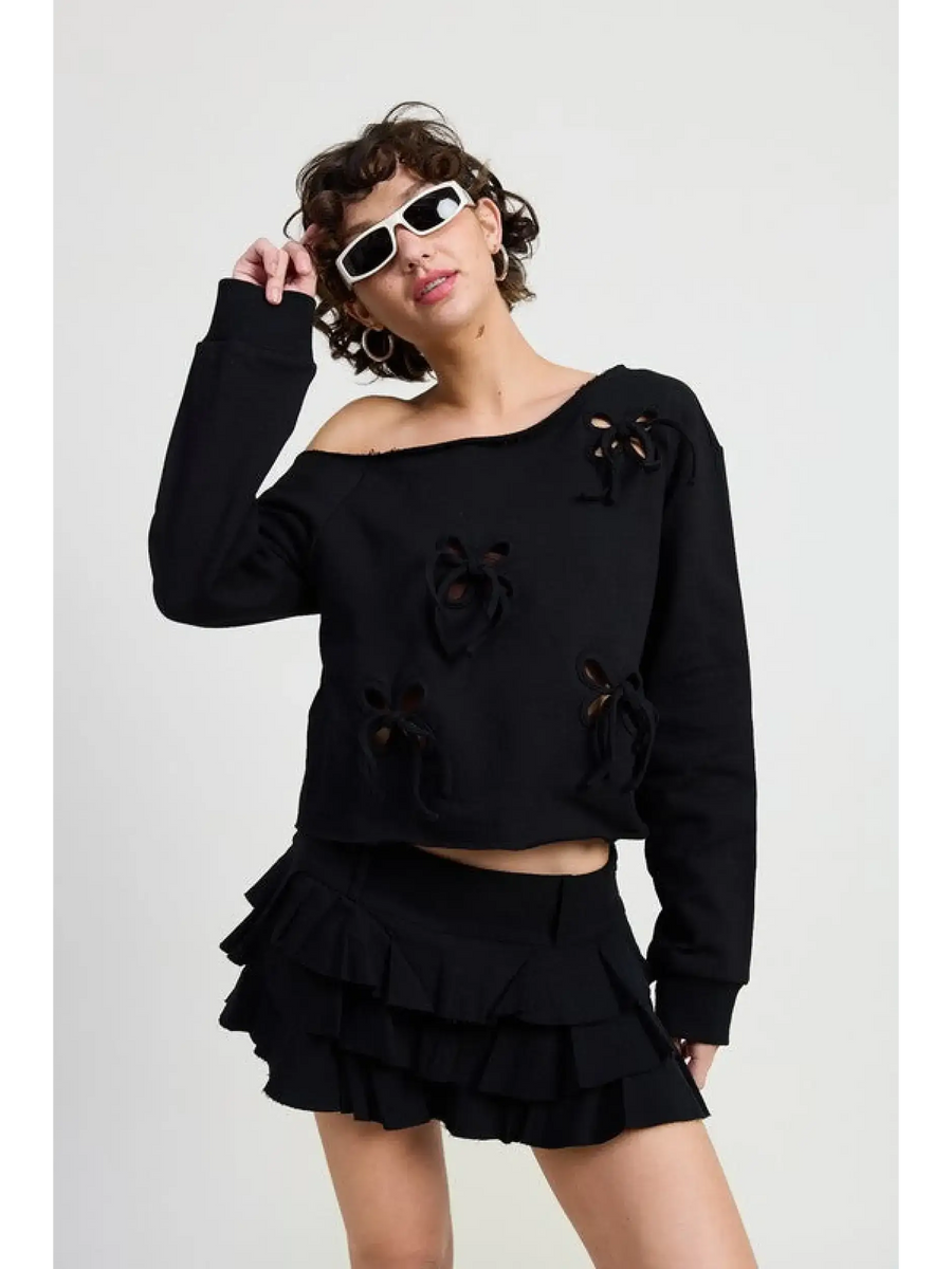 Emory Park off shoulder distressed top in black worn by model with ruffle mini skirt and white sunglasses