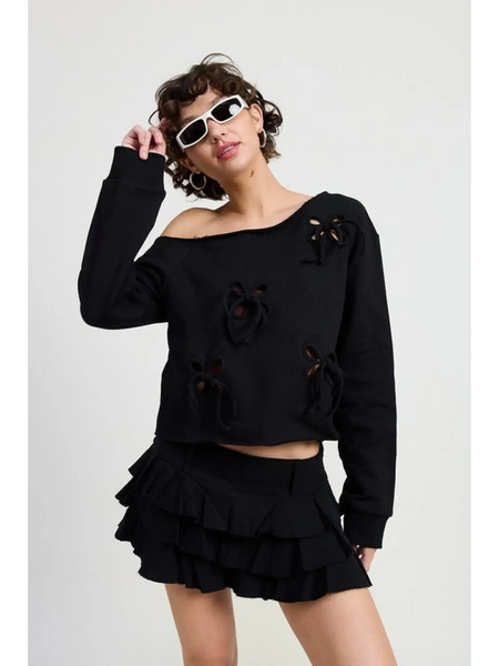 Emory Park off shoulder distressed top in black worn by model with ruffle mini skirt and white sunglasses
