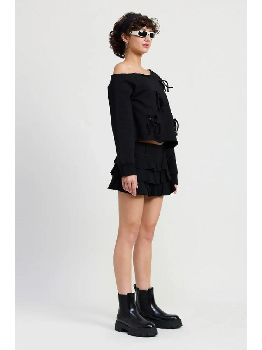 Emory Park black Off Shoulder Distressed Top paired with a black ruffled skirt and black ankle boots