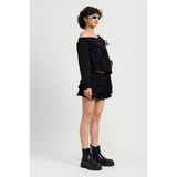 Emory Park black Off Shoulder Distressed Top paired with a black ruffled skirt and black ankle boots