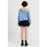 Emory Park Off Shoulder Distressed Top in blue worn by model with black ruffle skirt and black boots