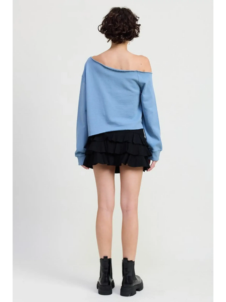 Emory Park Off Shoulder Distressed Top in blue worn by model with black ruffle skirt and black boots