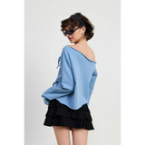 Emory Park Off Shoulder Distressed Top in blue worn by model with black ruffled skirt and sunglasses