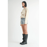 Emory Park off shoulder distressed top beige long sleeve paired with denim shorts and black boots