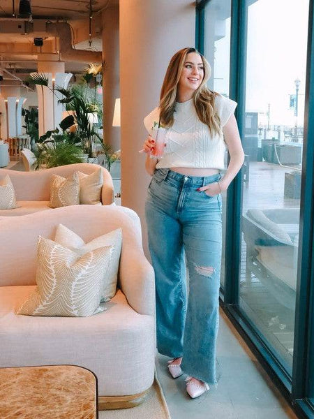 Woman wearing Rag Company pearl embellished summer sandals with casual jeans and white top in bright indoor setting