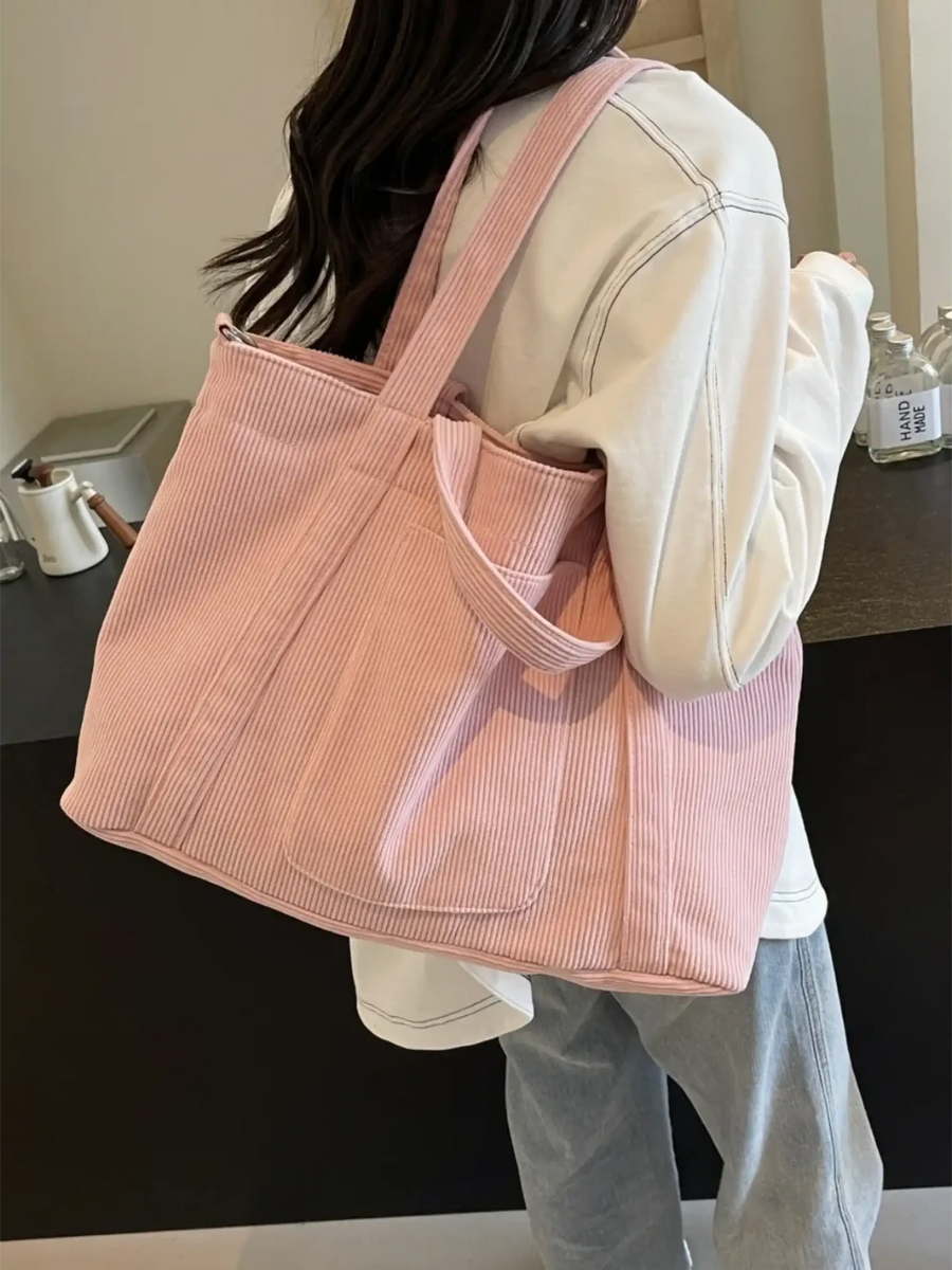 Lightweight Ladies duffle bag in pink corduroy fabric worn on shoulder by woman