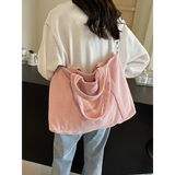 Lightweight ladies duffle bag in pink corduroy style worn by woman with white shirt and jeans