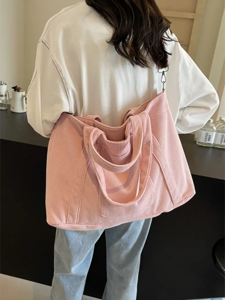 Lightweight ladies duffle bag in soft pink fabric worn over shoulder by woman in casual outfit