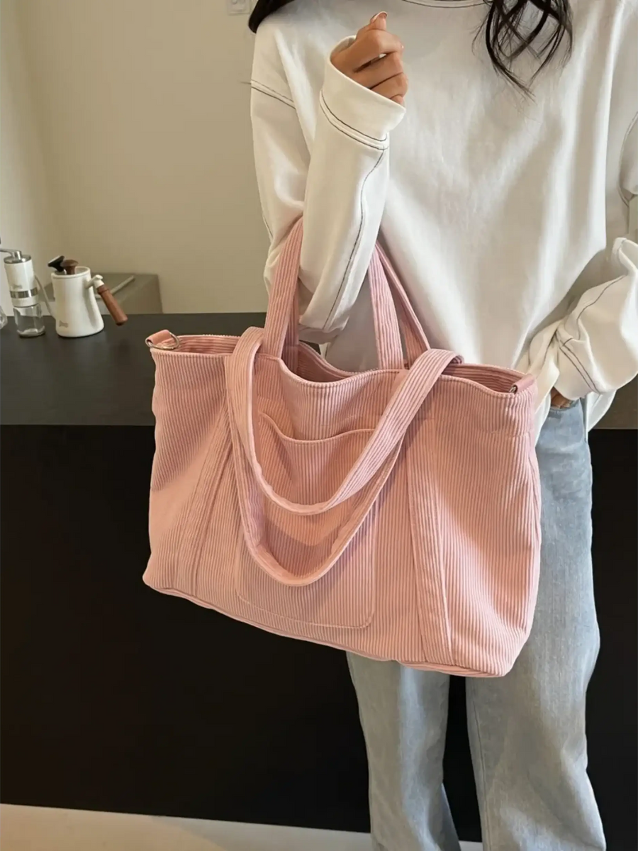 Lightweight Ladies duffle bag in soft pink corduroy fabric held by woman in casual white top and jeans