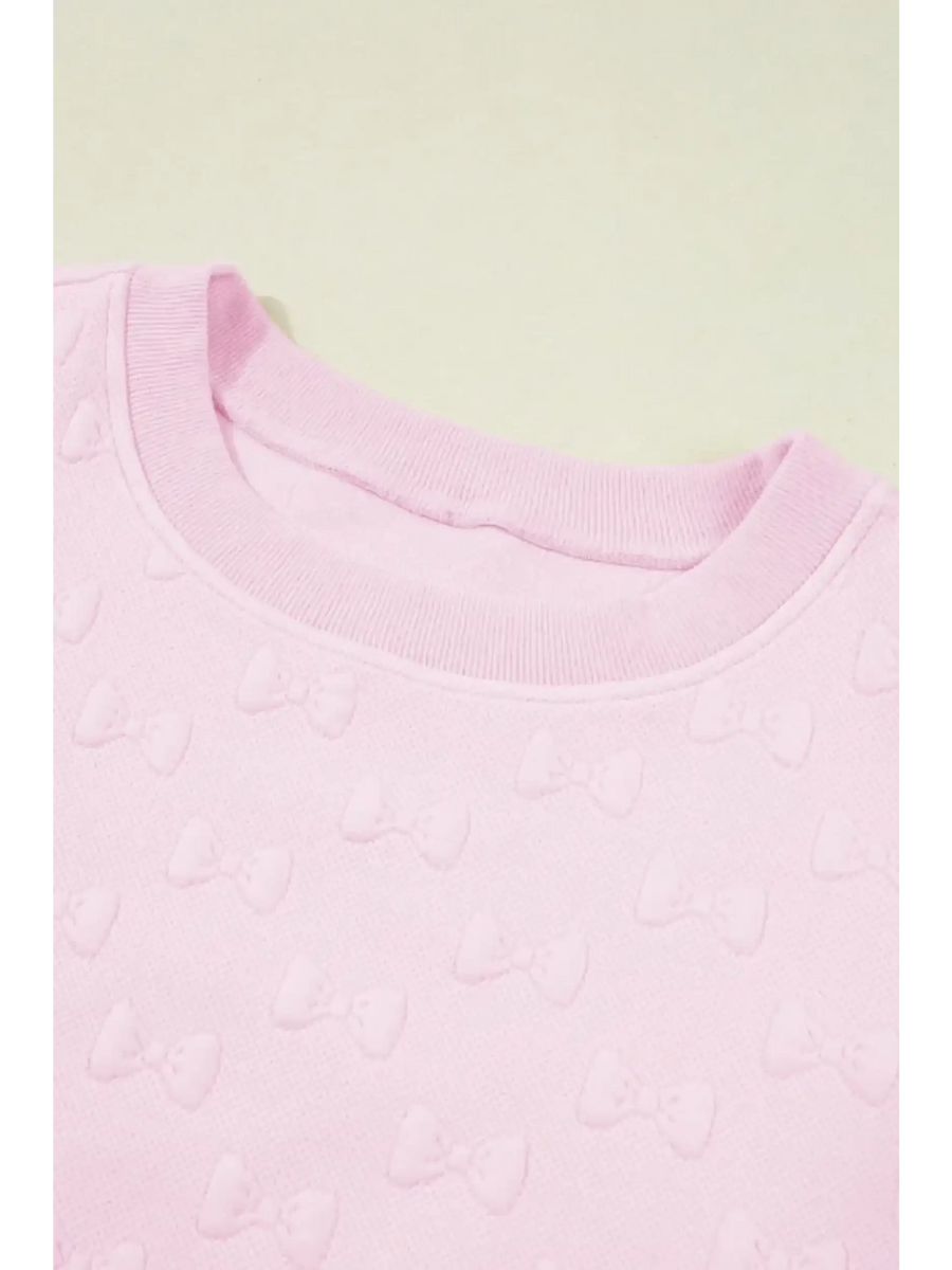 Close-up of pink summer short set for women featuring textured bow patterns on soft fabric