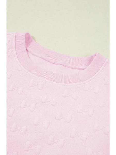 Close-up of pink summer short set for women featuring textured bow patterns on soft fabric