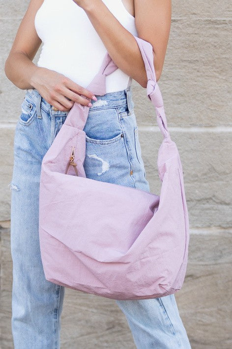 Piper Oversized Nylon Carryall Bag for Travel in light pink worn by a woman with casual denim jeans and white tank top