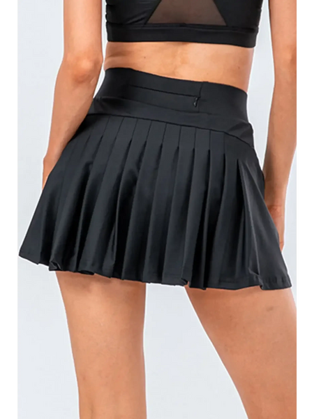 Babe Beachwear black pleated tennis skirt with pockets worn by model from the back