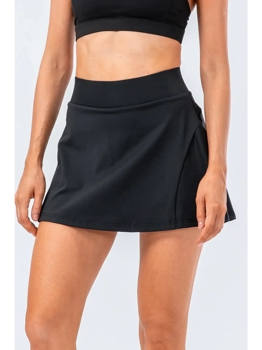 Babe Beachwear black pleated tennis skirt with pockets worn by woman with black crop top