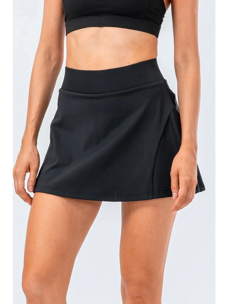 Babe Beachwear black pleated tennis skirt with pockets worn by woman with black crop top