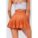 Babe Beachwear pleated tennis skirt with pockets in orange worn by woman from back