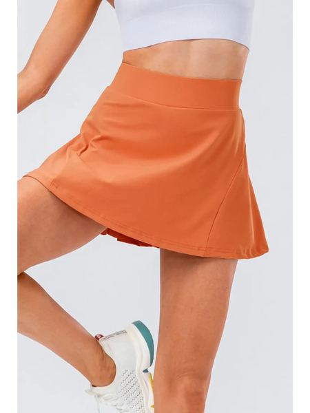 Babe Beachwear orange pleated tennis skirt with pockets worn with white athletic shoes