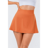 Babe Beachwear orange pleated tennis skirt with pockets worn with white crop top