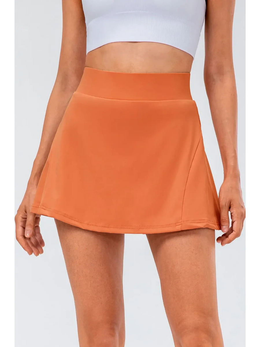 Babe Beachwear pleated tennis skirt with pockets in orange worn with white crop top