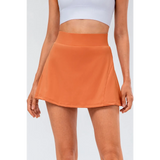 Babe Beachwear pleated tennis skirt with pockets in orange worn with white crop top