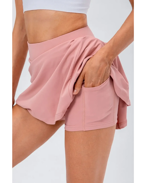 Babe Beachwear pleated tennis skirt with pockets in light pink, featuring built-in shorts and a high waistband