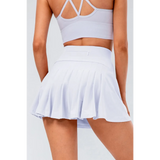 Babe Beachwear pleated tennis skirt with pockets in white worn from the back with a sports bra