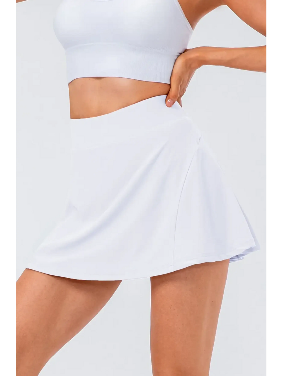 White pleated tennis skirt with pockets by Babe Beachwear worn with a white crop top