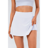 Babe Beachwear white pleated tennis skirt with pockets worn by woman with matching crop top